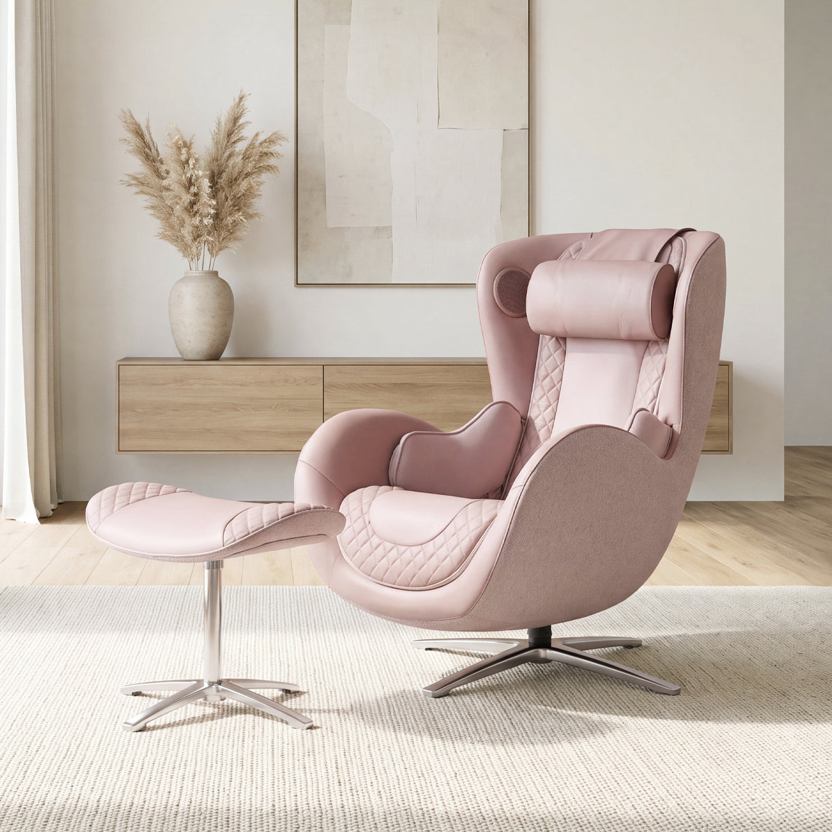 N-0003PR-V2, Pale Rose ergonomic massage armchair with matching ottoman in a bright, elegant American home during a sunny daylight saving time afternoon. The stylish dusty pink leather and fabric lounger features intricate diamond quilting, resting on a neutral off-white textured rug. In the background, soft natural sunlight illuminates a modern floating wooden console table adorned with a vase of fluffy pampas grass and minimalist abstract wall art.