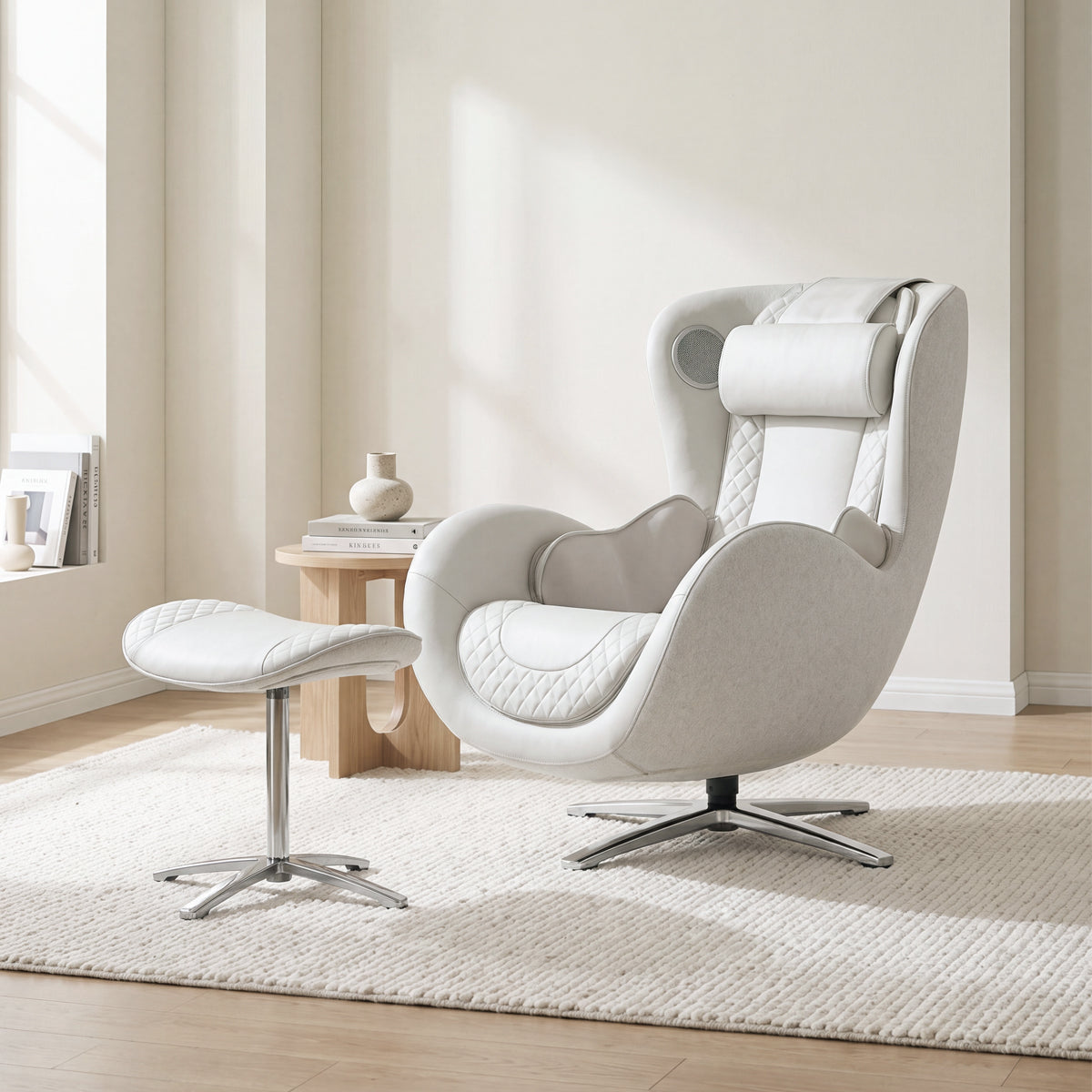 N-0003EW-V2, Elder White ergonomic massage armchair with matching ottoman in a bright, tranquil American living room during a sunny daylight saving time afternoon. The elegant off-white leather and light grey fabric lounger showcases detailed diamond quilting, resting on a plush white woven area rug over light wood flooring. In the background, warm natural sunlight creates soft shadows on the minimalist cream walls, highlighting a small wooden side table with stacked books and a ceramic vase.