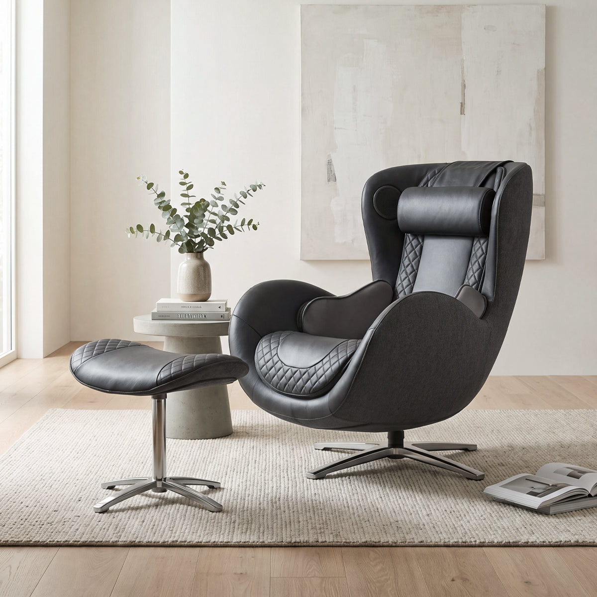 N-0003BL-V2, Space Black ergonomic massage armchair with matching ottoman in a bright, modern American living room during a sunny daylight saving time afternoon. The sleek, premium black leather and charcoal fabric lounger features elegant diamond-quilted details, resting on a light-colored woven area rug over hardwood flooring. In the background, soft natural light illuminates the space, highlighting a minimalist concrete side table with a vase of eucalyptus branches and an abstract textured wall painting.