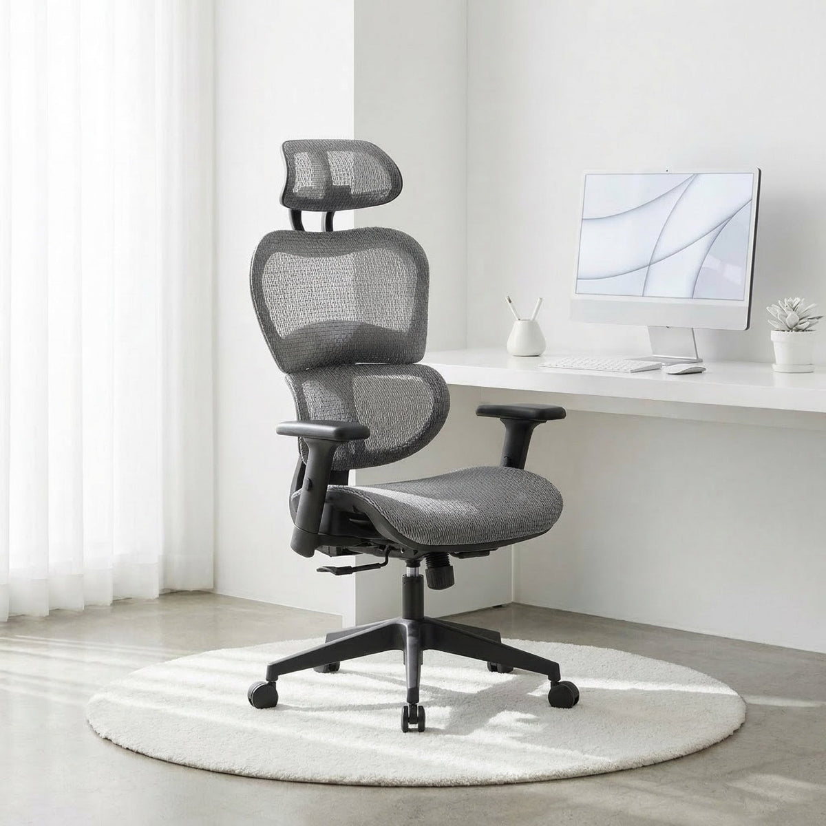 NHO-0001GR-L,Light Grey ergonomic office chair in a modern office setting with a desk and computer monitor.