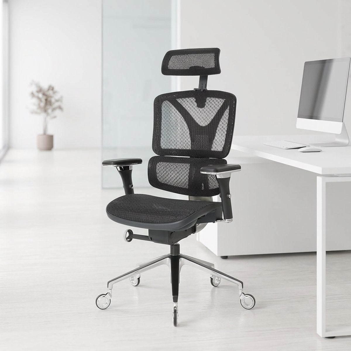 NHO-0005BL,Black office chair in a modern office setting with a white desk and computer monitor.